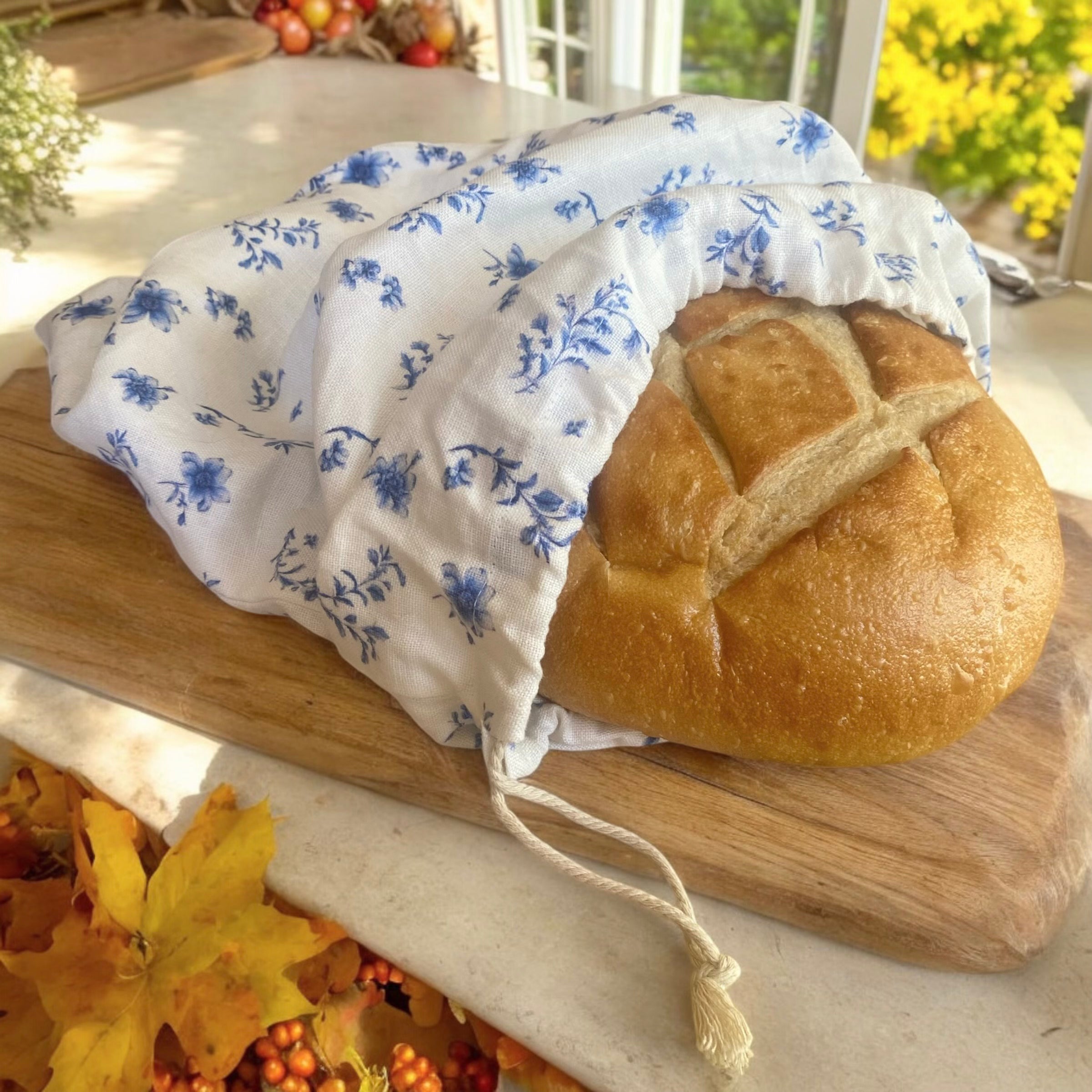 Handmade floral linen bread bag for French bread, styled in a cozy fall kitchen with seasonal decor.